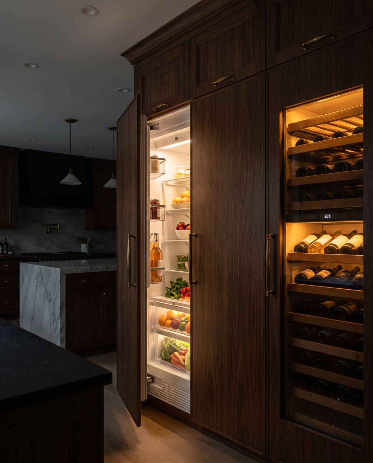 Open refrigerator column with warmly lit stocked interior beside an amber wine column